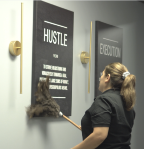 Professional cleaner dusting wall décor during commercial office cleaning in Houston, TX.